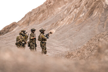 Special Forces Team Standing Together in Desert Mountain Terrain – Tactical Soldiers in Full Gear...