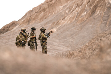 Special Forces Team Standing Together in Desert Mountain Terrain – Tactical Soldiers in Full Gear...