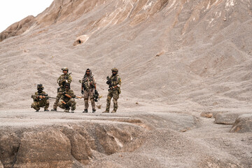 Special Forces Team Standing Together in Desert Mountain Terrain – Tactical Soldiers in Full Gear...
