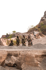 Special Forces Team Standing Together in Desert Mountain Terrain – Tactical Soldiers in Full Gear...
