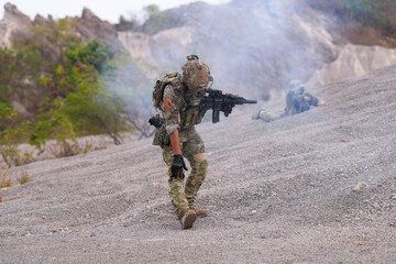 Special forces soldier uses a radio during a tactical operation while red flare smoke spreads...