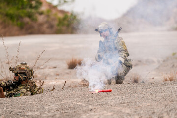 Special forces soldier uses a radio during a tactical operation while red flare smoke spreads...
