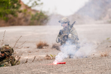 Special forces soldier uses a radio during a tactical operation while red flare smoke spreads...