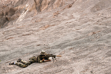 Two Sniper Soldiers in Camouflage Gear Aiming from Concealed Positions on Rocky Terrain – Tactical Recon, Long-Range Precision Shooting, Military Field Operation in Harsh Environment