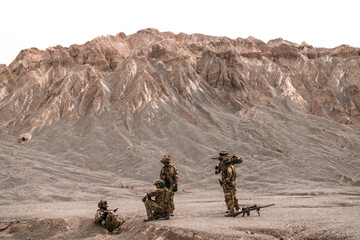 A group of special forces soldiers conduct a briefing in a rugged desert mountain environment....