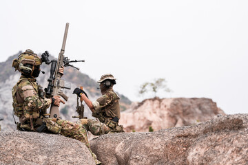 Two Soldiers Preparing Weapon on Rocky Terrain – Tactical Readiness and Military Coordination...