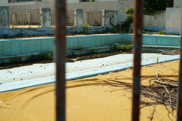Abandoned Outdoor Pool Seen Through Rusty Bars