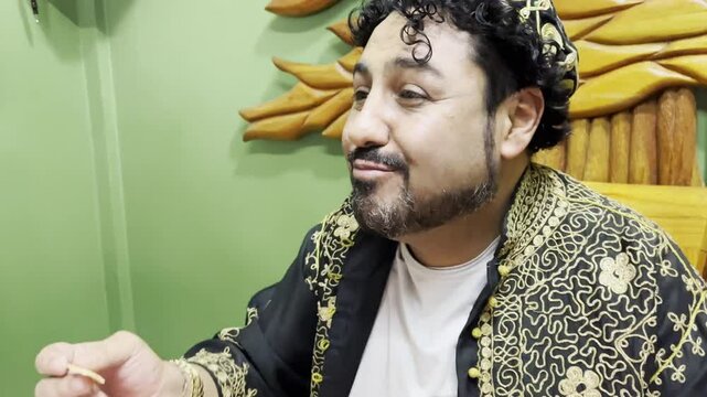 Horizontal 4k video of a Lebanese man enjoying his delicious traditional meal while smiling, with his hands taking the pita bread to accompany his hummus.	