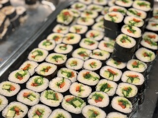 Variety of Freshly Prepared Sushi Rolls Beautifully Arranged on Display for Patrons. Exquisite and...