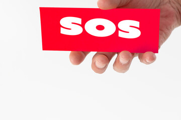 A hand holding a paper displaying text SOS (save our Soul)