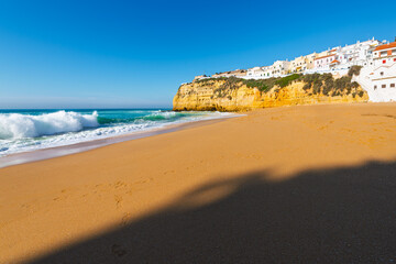 The sandy Praia de Carvoeiro beach with the Alto da Praia do Carvoeiro upper town of whitewashed buildings above in Carvoeiro, Portugal, Algarve region.
