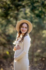 A beautiful pregnant woman is posing gracefully amidst a lush green setting, radiating immense joy and tranquility
