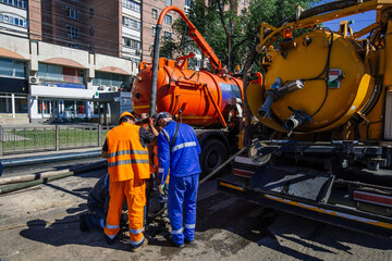 Workers cleaning sewer and pumping sewage into septic tank