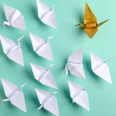 Top‑down view against a pale mint backdrop- a flock of twenty white origami birds