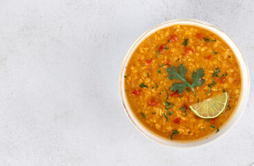 Traditional Indian dal soup with red lentils, spices, fresh cilantro and lime on a white background. Indian food