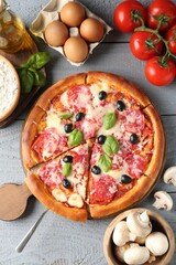 Tasty pizza and ingredients on grey wooden table, flat lay