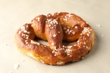 Tasty pretzels with salt on beige background, closeup