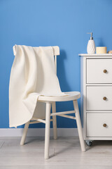 Clean waffle towel on chair and dresser near blue wall