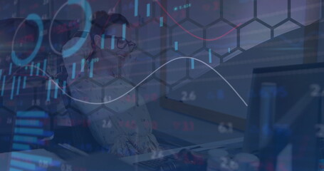 Leaning analyst examining data charts on computer monitor at office desk, with keyboard and mouse