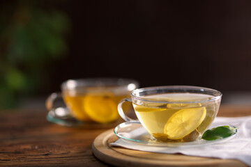 Cups of tasty green tea with lemon on wooden table, closeup. Space for text