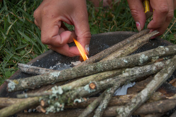 Woman lighting kindling with match in a clay pot