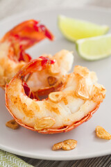 Homemade fried lobster tails with fried garlic slices and lime wedges in the back (Selective Focus, Focus on the front of the first tail)