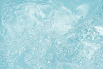 Blue water with ripples on the surface. Defocus blurred transparent blue colored clear calm water surface texture with splashes and bubbles. Water waves with shining pattern texture background.