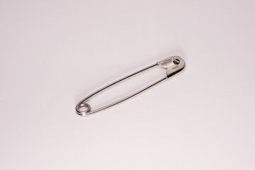 A close-up of a silver safety pin in the closed position, isolated on a white background. Ideal for concepts of sewing, safety, minimalism, or everyday objects