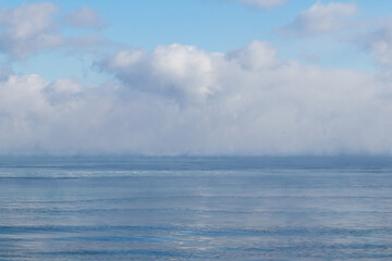 Frozen lake in winter with steamy puffy clouds on horizon