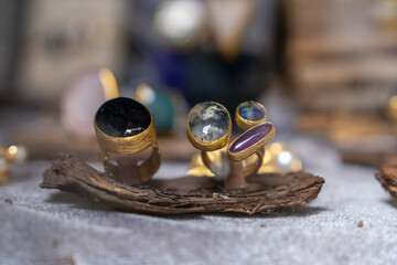 A stylish collection of gemstone rings elegantly arranged on a piece of driftwood. the vibrant gems set in gold create a captivating focus, highlighting contemporary jewelry trends.