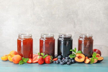 Different jams in jars and ingredients on blue wooden table. Space for text