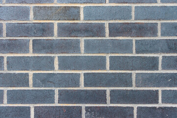 Head on view of a wall of grey blue bricks with white mortar
