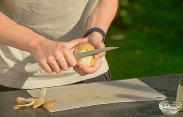 man's hands with potatoes and knife.man peeling raw potatoes with knife close-up