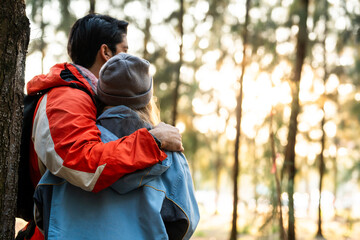 Couple Hugging in Forest at Sunset. Rear View of Romantic Travelers in Warm Winter Clothes Standing Together, Embracing Peacefully While Enjoying the Tranquil Nature and Soft Golden Light