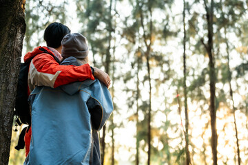 Couple Hugging in Forest at Sunset. Rear View of Romantic Travelers in Warm Winter Clothes Standing Together, Embracing Peacefully While Enjoying the Tranquil Nature and Soft Golden Light