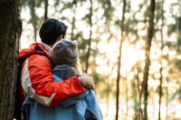 Couple Hugging in Forest at Sunset. Rear View of Romantic Travelers in Warm Winter Clothes Standing Together, Embracing Peacefully While Enjoying the Tranquil Nature and Soft Golden Light