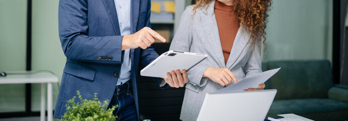 Professional man and woman reviewing printed business documents in modern office setting. Concept...