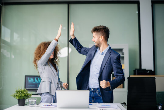 Happy business team cheering in office after project success. Celebration, teamwork victory, achievement
