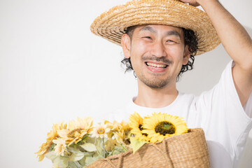 ひまわりを持つ麦わら帽子を被った中年男性　明るい楽しいおじさん