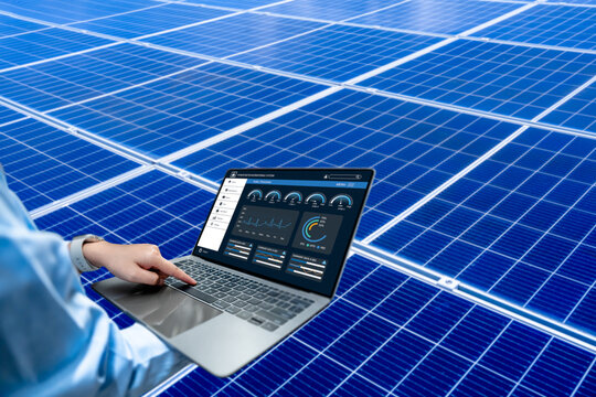 Engineer using laptop to monitor solar energy performance dashboard in solar power plant, renewable energy technology and data analytics for efficient clean energy management system