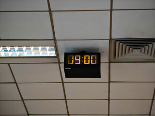 Old style electronic watch on the ceiling. Vintage digital clock. Industrial digital clock with luminescent digits
