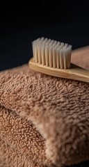 Close-up of a light brown bamboo toothbrush resting on a folded brown towel.  The bristles are visible, and the towel's texture is prominent