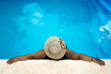 Woman with sunhat relaxing by the pool