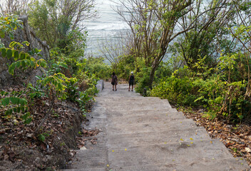 Tourist is descending the stairs to Green Bowl Beach in Bali, Indonesia.