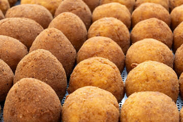 Arancini Sicilian, deep-fried rice balls made with risotto, filled with ingredients mozzarella, ragu, peas, coated in breadcrumbs fried to crispy, brown on market in Palermo, Sicily