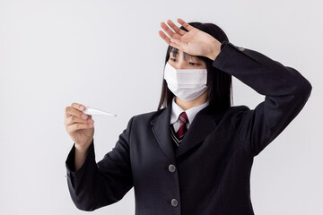 受験日へ向けマスクをして健康に気を遣う女子高生 体温計