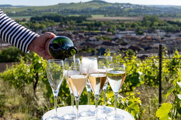 Pouring and tasting of white and rose sparkling wine brut, grand reserve, champagne in Ay-Champagne on green hilly vineyards in old wine making village in Vallee de la Marne, Champagne region, France