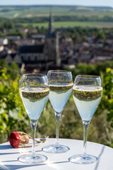 Pouring and tasting of dry sparkling wine brut, grand reserve, champagne in Ay-Champagne on green hilly vineyards in old wine making village in Vallee de la Marne, Champagne region, France
