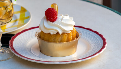 French cuisine, fresh baked baba au rum cake with chantilly cream, sweet dessert with rum and glasses of champagne wine close up