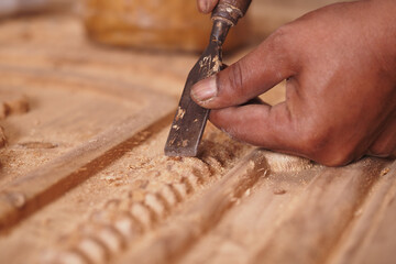 Hand carving wood details in a workshop at dusk